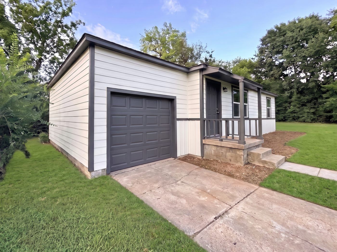 The same North Tulsa house after Okie Native Homebuyers' full remodel — new siding, roof, porch, and lawn